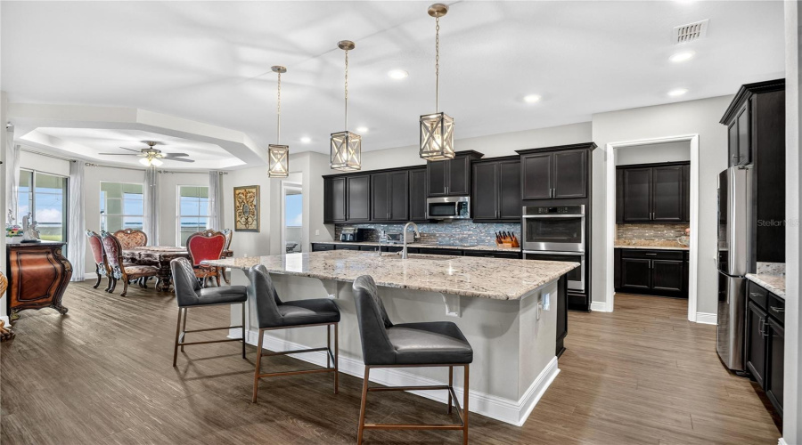 Gourmet kitchen featuring a large center island, pendant lighting, granite countertops, and stainless steel appliances.