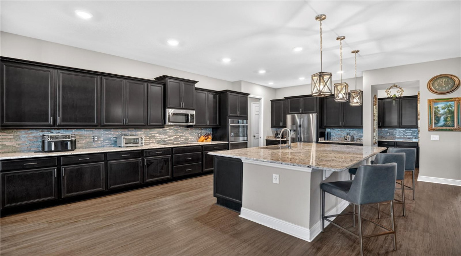 Expanded kitchen workspace with extensive cabinetry, tile backsplash, and generous counter space.