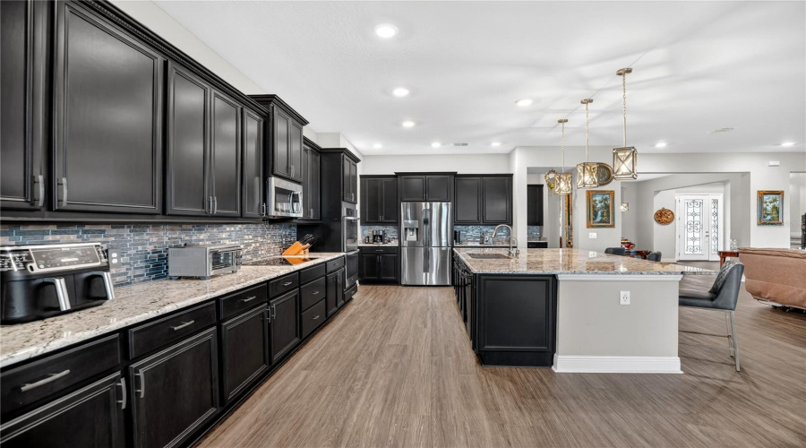 Alternate view of the kitchen highlighting the island, storage, and open connection to the living areas.