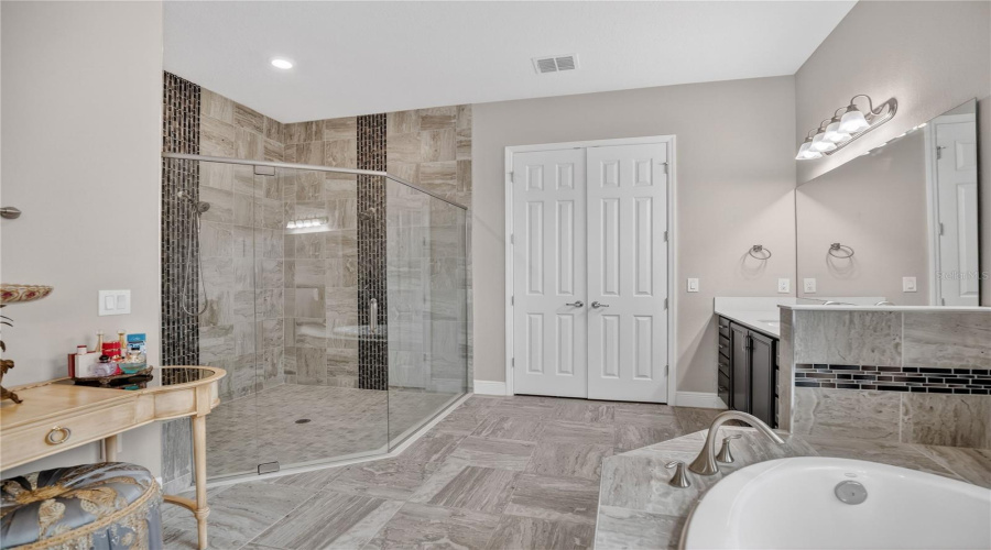 Primary bathroom featuring a glass-enclosed walk-in shower and tiled flooring.