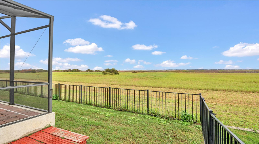 Uninterrupted lake views beyond backyard and screened patio