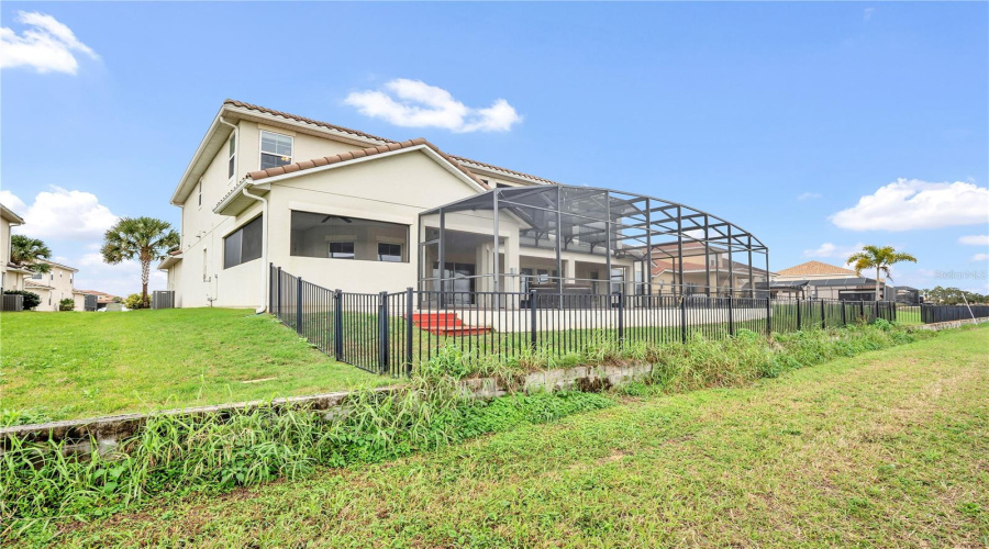 Rear exterior showcasing screened lanai and fenced backyard