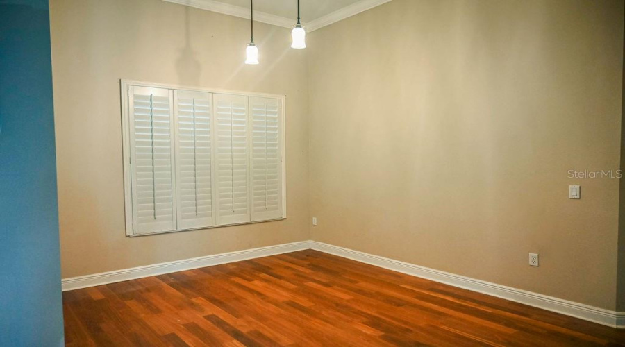 Dining room with plantation shutters and wood plank flooring. Located to the left upon entry into the home.