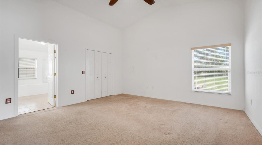 The Primary Bedroom offers high ceilings, a ceiling fan, walk-in closet, and ensuite. (New flooring and interior paint since original photos were taken)