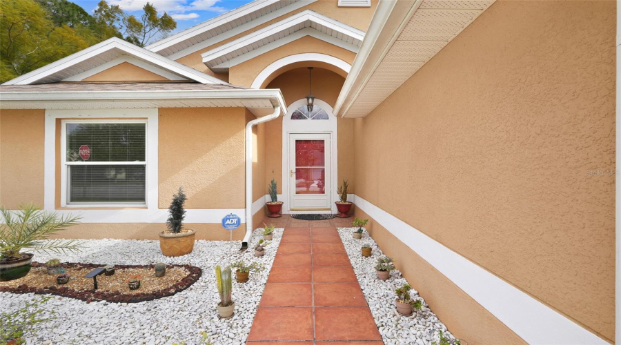 The tiled walkway leads to the covered front entry of the home.