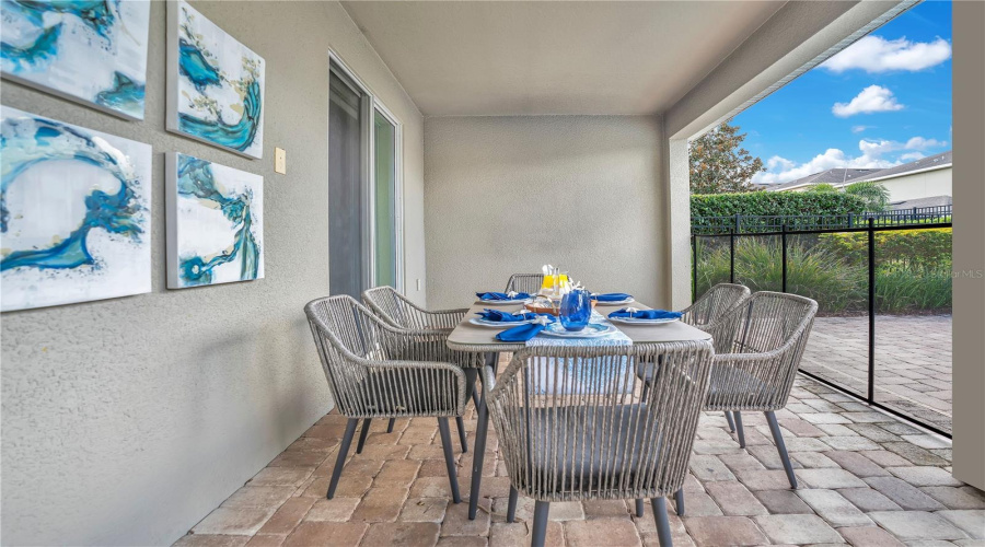 Covered lanai dining space ideal for al fresco meals with views of the private pool and patio