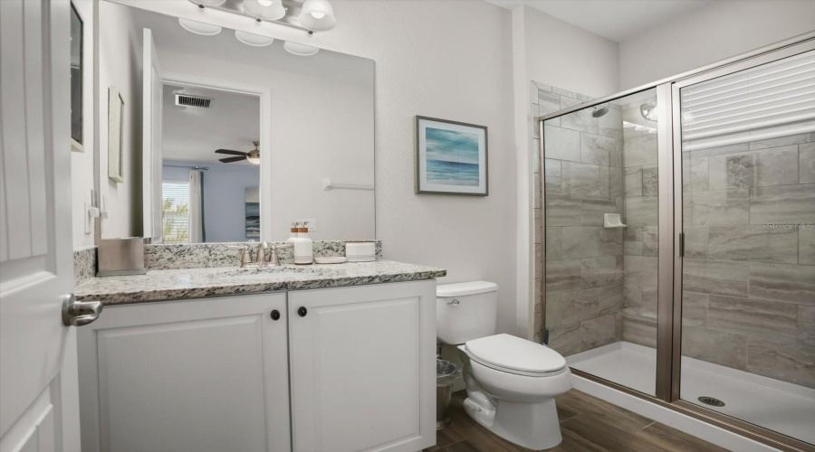 Bathroom with granite countertops and walk in shower, continuing the home’s cohesive design.