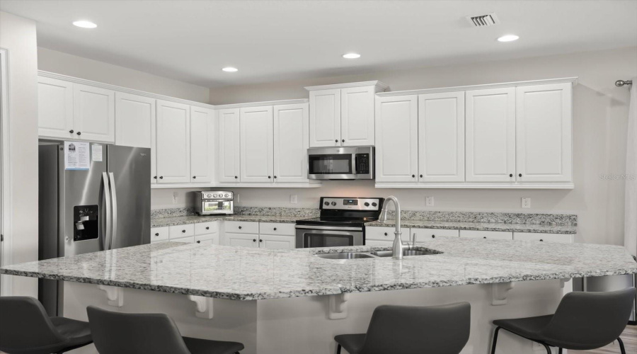 Kitchen featuring granite countertops, stainless steel appliances, and a large breakfast bar ideal for entertaining.