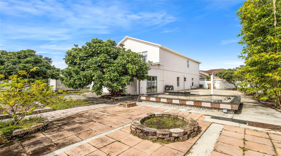 Backyard fully fenced with a large concrete Fully fenced backyard with a large concrete patio and a decorative pond feature