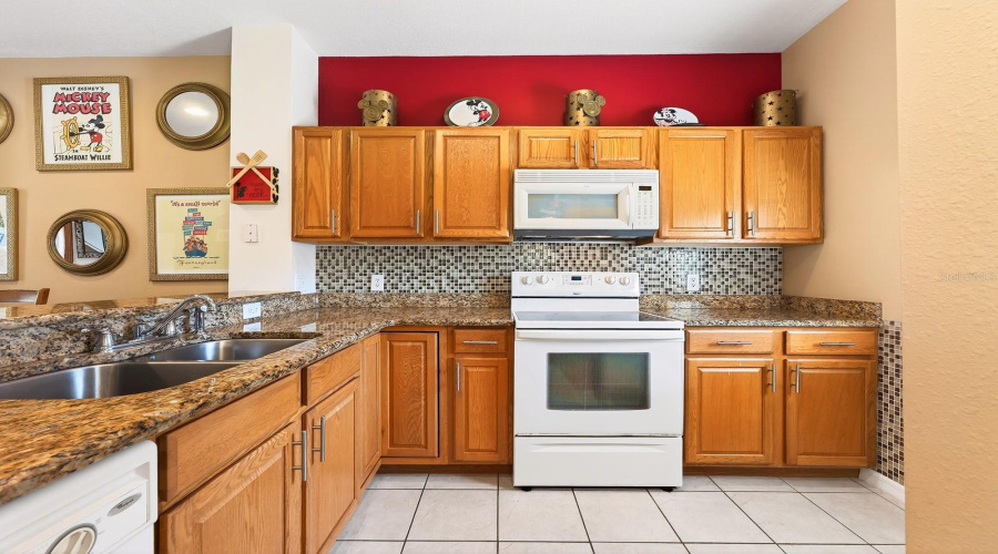 The Kitchen is both stylish and functional, featuring solid wood cabinetry, GRANITE COUNTERTOPS, a sleek tile backsplash, and a convenient breakfast bar for casual dining.