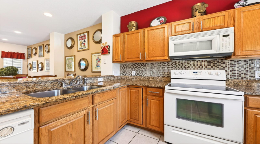 The Kitchen is both stylish and functional, featuring solid wood cabinetry, GRANITE COUNTERTOPS, a sleek tile backsplash, and a convenient breakfast bar for casual dining.