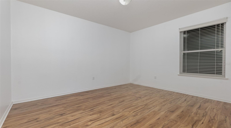 Bedroom 3 with neutral toned laminate flooring and ceiling fan.