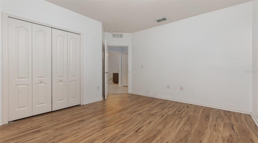 Bedroom 3 with neutral toned laminate flooring and ceiling fan.