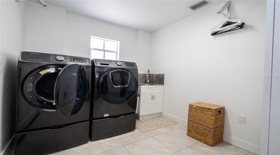 Laundry room with high end machines and a private sink to help with day to day laundry.