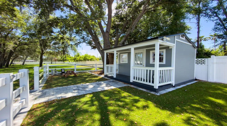 A charming farmhouse-style private cottage tucked beneath mature trees, offering a serene and versatile space for guests, work, or quiet moments.