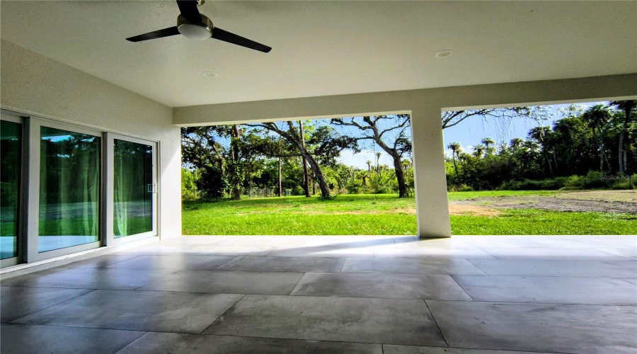 View from inside rear patio to back yard. Currently has electrical fence across back patio edge to keep critters off the patio. It will be removed upon closing.