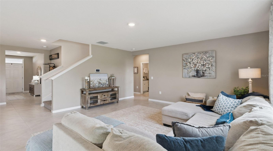 View of the family room from the back of the house. Nice open floor plan providing views of the front foyer, staircase and hallway leading to the guest bedroom and bathroom.