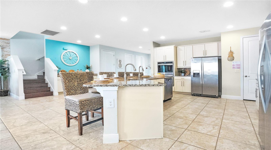 Beautifully designed kitchen with 42-inch white shaker cabinetry, stainless steel appliances, breakfast bar seating for eight, and an open layout that flows seamlessly into the living areas