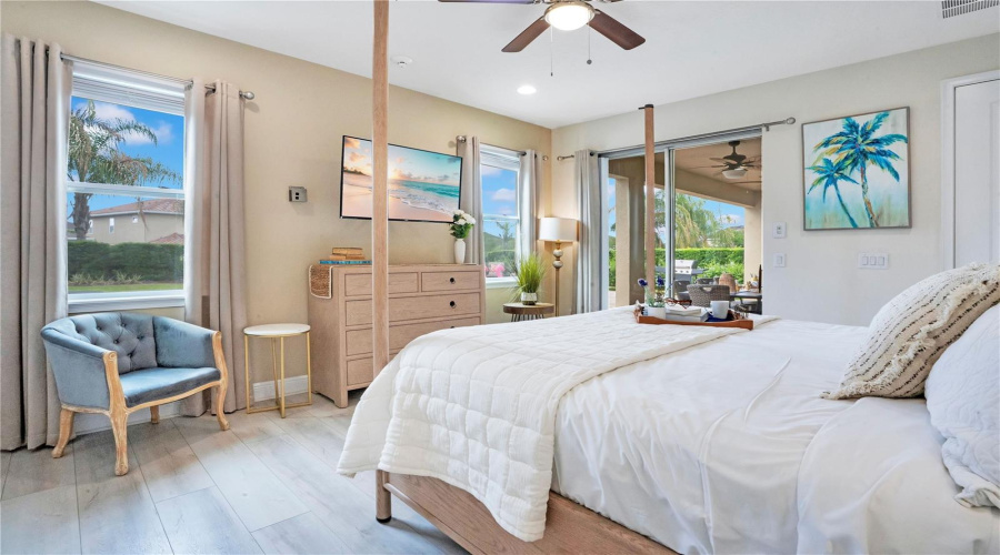 Downstairs primary suite featuring spacious accommodations and sliding glass doors to the lanai
