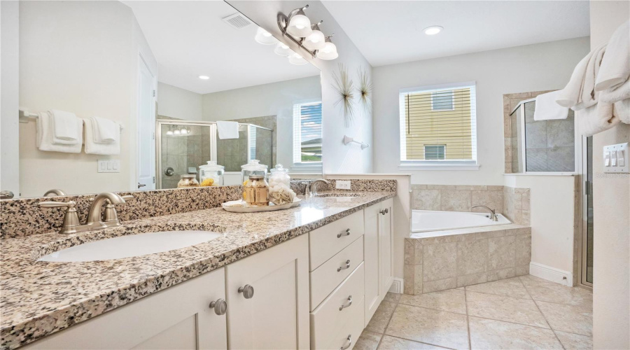 Spa like ensuite to the primary with dual vanities, granite counters, soaking tub, and walk-in shower