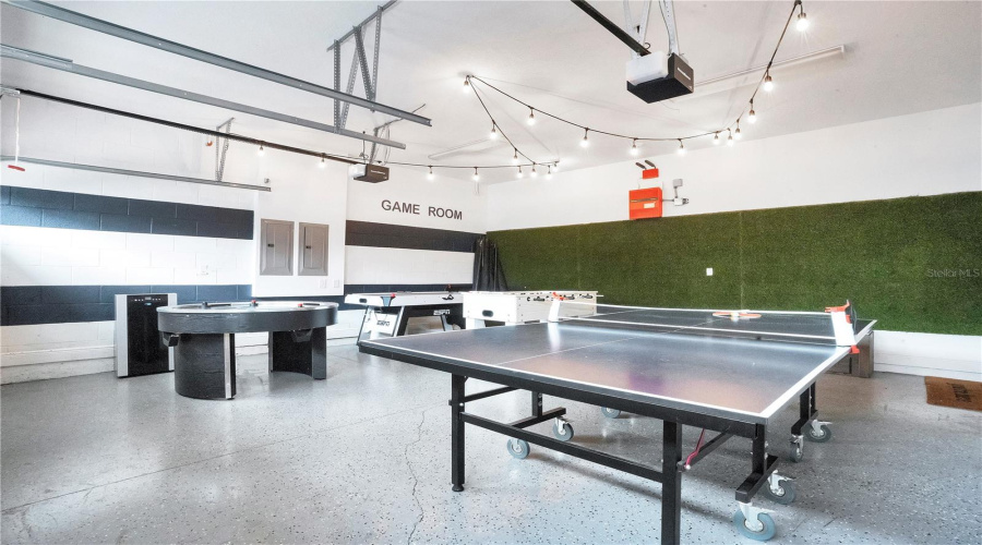 Resort-style garage game room featuring premium epoxy floors, ping pong, and entertainment space