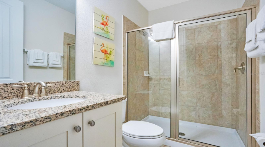 Private ensuite bathroom to Bedroom #5 featuring granite counters and walk-in glass shower