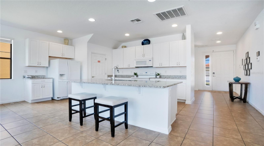 Bright kitchen with white cabinets and breakfast bar seating.