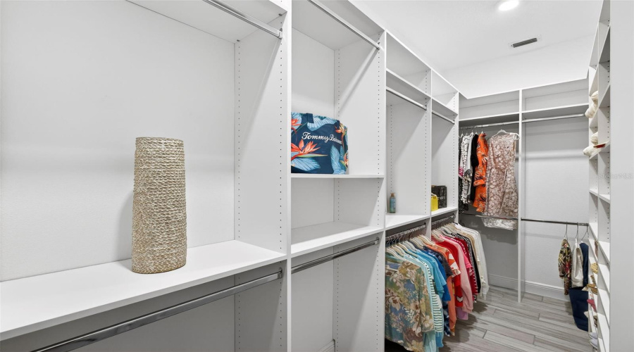 Walk-in primary closet with custom cabinetry