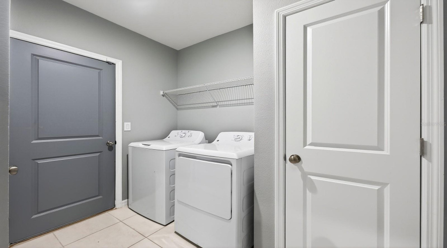 A DEDICATED LAUNDRY ROOM with shelving and a linen closet adds convenience and extra storage.
