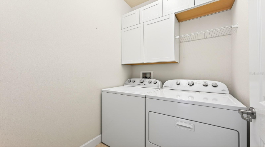 A DEDICATED LAUNDRY ROOM with cabinetry plus included washer and dryer adds everyday convenience.