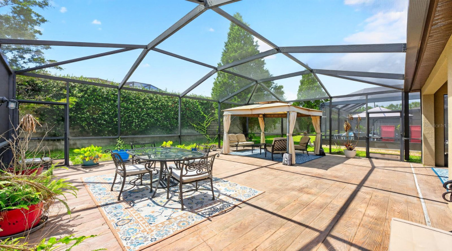 The lanai features STYLISH CONCRETE WOOD-LOOK FLOORING and two screened access doors to the backyard.