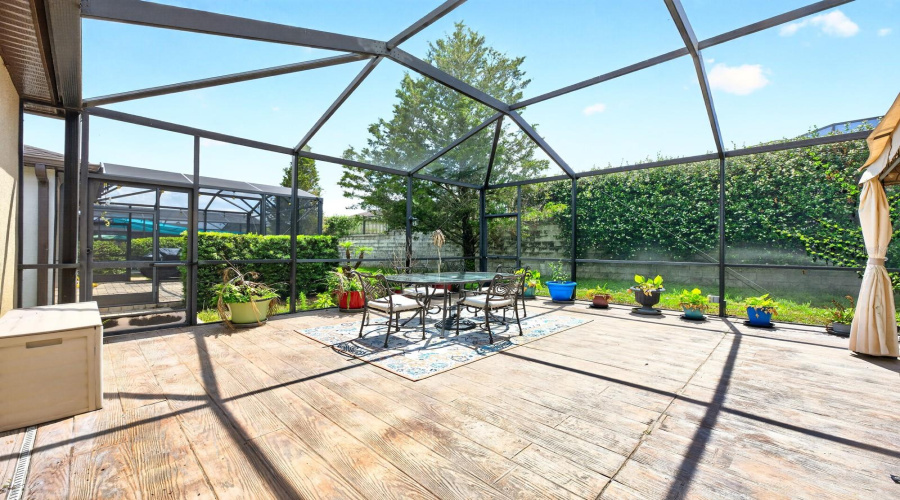 The lanai features STYLISH CONCRETE WOOD-LOOK FLOORING and two screened access doors to the backyard.