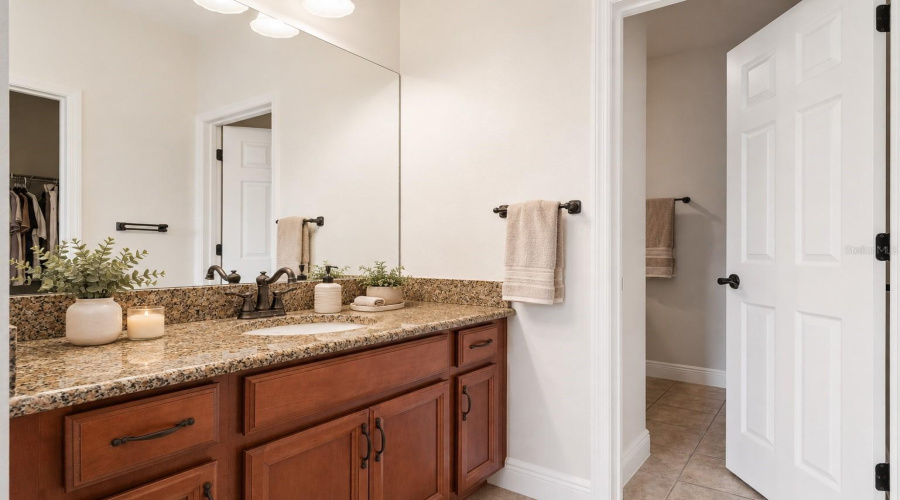 Thoughtfully designed for both privacy and convenience, this shared bath features separate vanities for each bedroom connected by a central tub and shower area