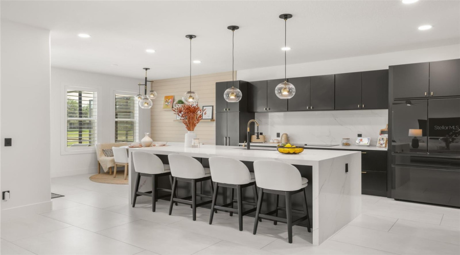 A dramatic waterfall island anchors the kitchen, paired with dark cabinetry, globe pendant lighting, and bar seating for everyday dining or entertaining.
