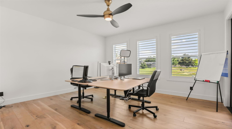 A dedicated office space features wood flooring, plantation shutters, and room for multiple workstations or flexible use.