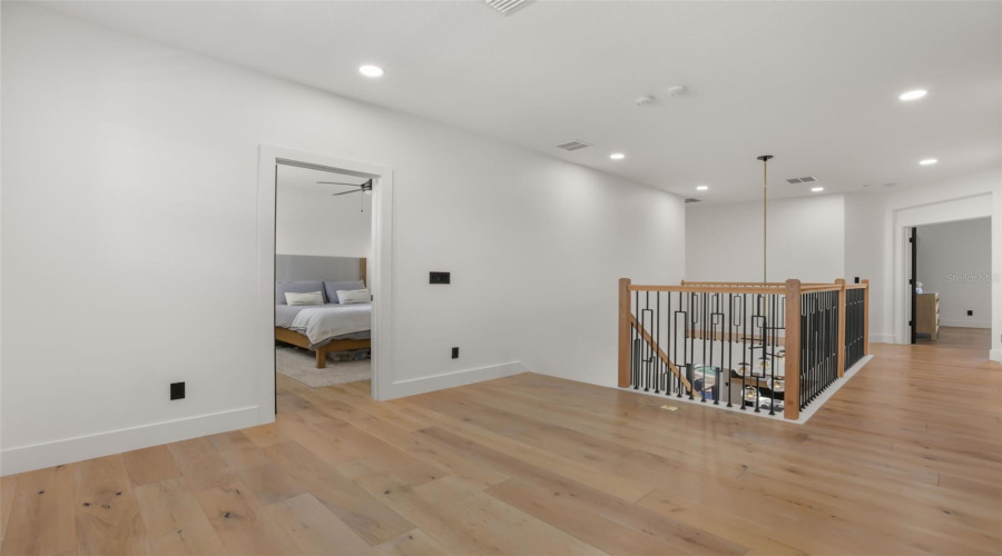 A bright upstairs hallway offers open sightlines over the staircase and connects the home’s private upper-level spaces.