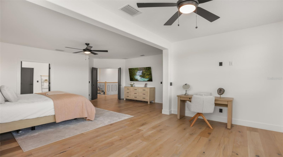 This wide bedroom view highlights the generous layout, plantation shutters, and dedicated desk or dressing nook.