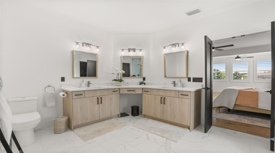 A spacious vanity layout with multiple sinks, light wood cabinetry, and framed mirrors offers both style and everyday function.