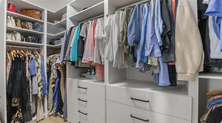 This custom closet includes drawer banks, open shelving, and multiple hanging sections for organized, accessible storage.