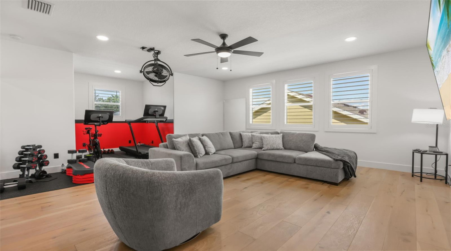 This spacious bonus room combines a lounge area with a dedicated fitness zone, offering flexibility for recreation, workouts, or media use.