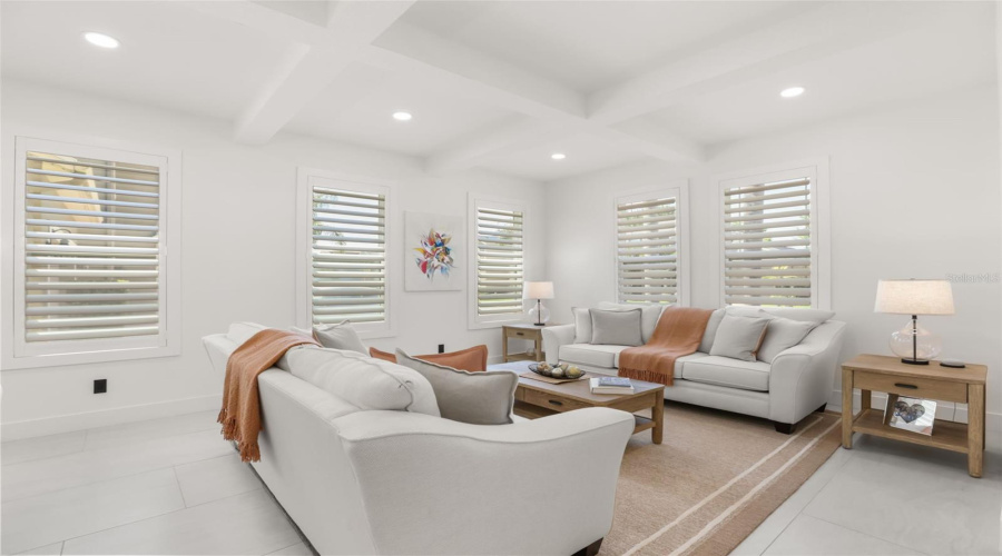 This inviting sitting area features plantation shutters, soft neutral finishes, and abundant natural light for a comfortable gathering space.
