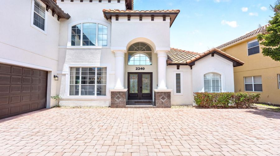 The home has OUTSTANDING CURB APPEAL, featuring a brick paver driveway, mature trees, lush landscaping, and a SPACIOUS 3-CAR GARAGE.