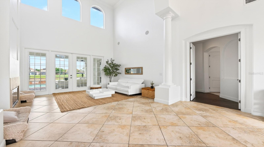 The formal Living Room is both elegant and inviting, featuring a COZY FIREPLACE and FRENCH DOORS that open directly to the outdoor living space.
