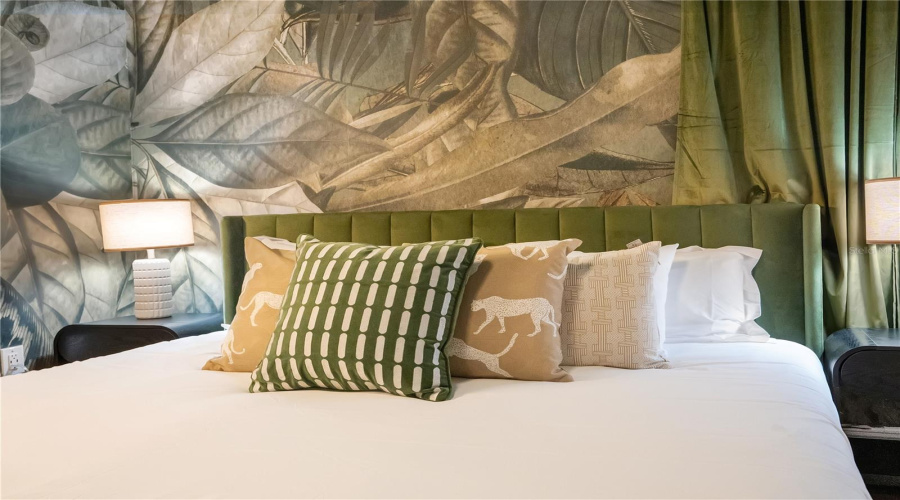Custom wall coverings, designer furnishings, and layered textures create an elevated tropical escape unlike a traditional vacation rental bedroom.