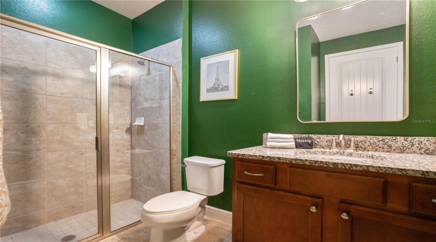 The coordinating ensuite bath continues the tropical design with designer finishes, spacious vanity, and walk-in shower.