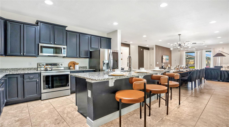 The heart of The WonderHouse features an open-concept kitchen with granite countertops, stainless steel appliances, abundant cabinetry, and expansive seating designed for gathering family and friends.