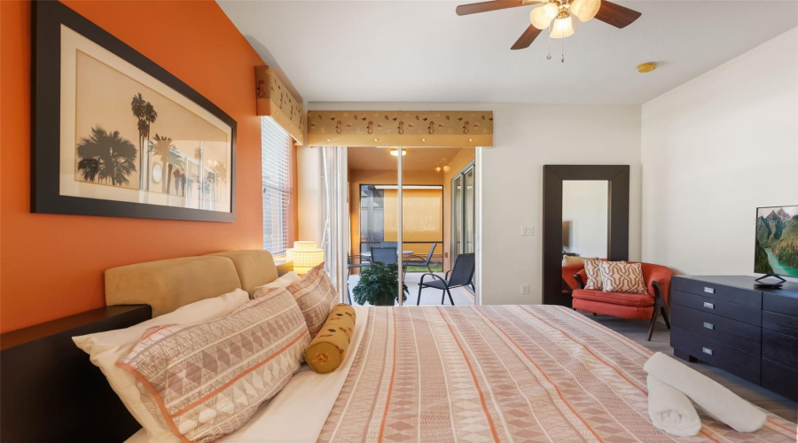 Another view of the primary bedroom highlighting the direct access to the covered lanai and screened pool area.