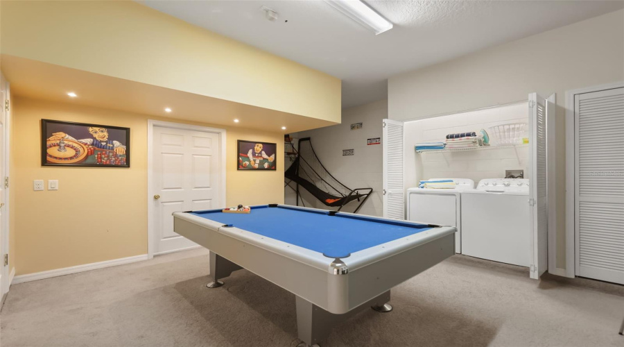 Garage games room complete with a pool table, basketball game, and laundry area for added entertainment.