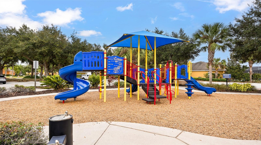 Community playground featuring shaded play equipment, slides, climbing structures, and landscaped surroundings, providing a fun outdoor space for owners and guests of all ages.