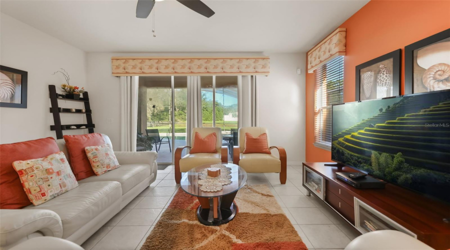 Spacious family room with sliding glass doors leading to the screened pool area, creating the perfect indoor-outdoor living experience.
